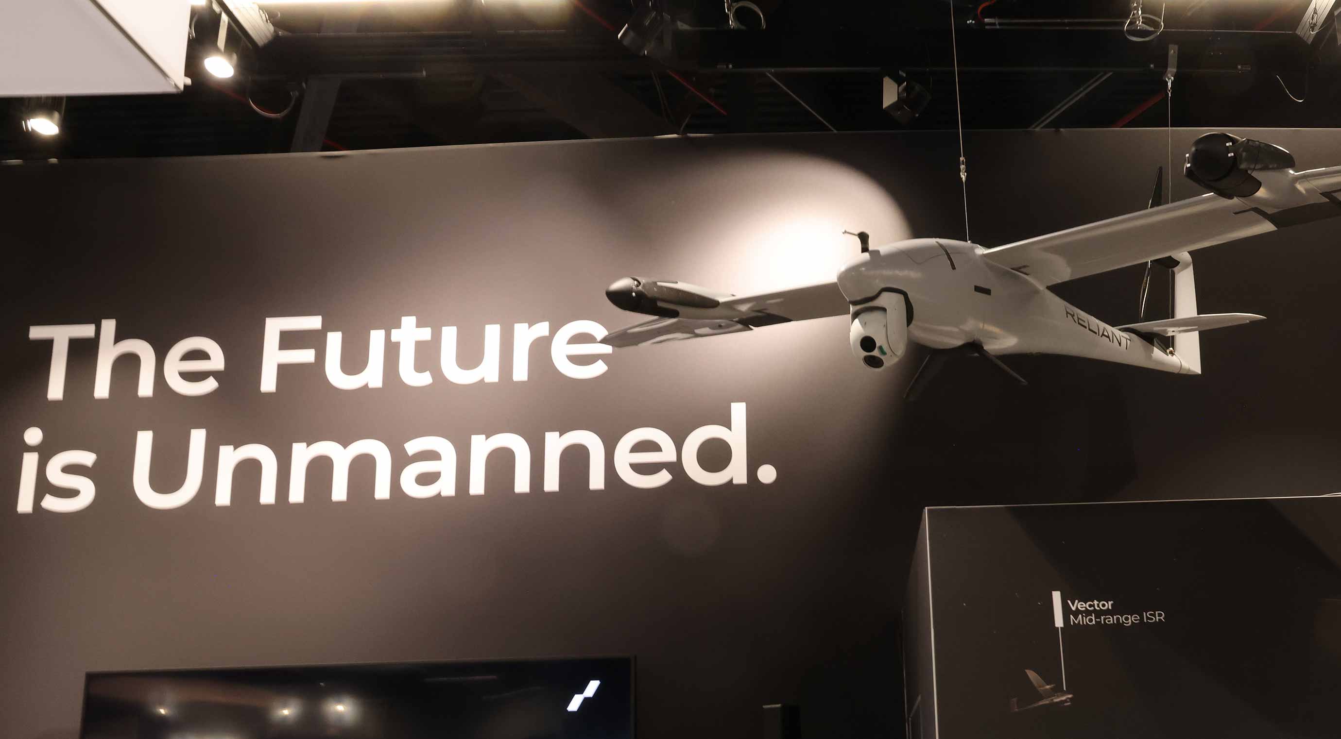 Drohne über Messestand mit Slogan „The Future is Unmanned“.