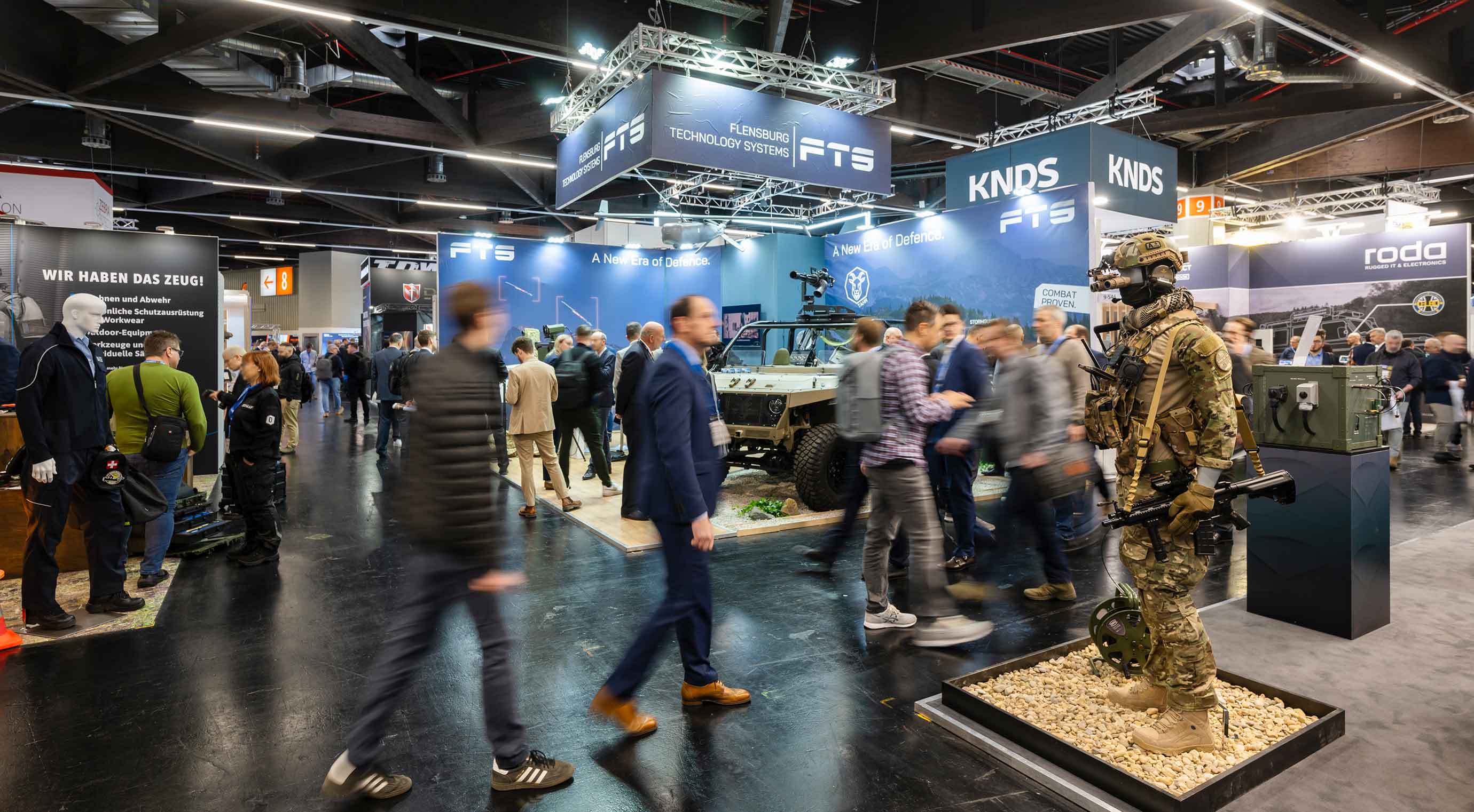 Besucher in Messehalle der Enforce Tac. Im Hintergrund sind Stände der Aussteller zu sehen.